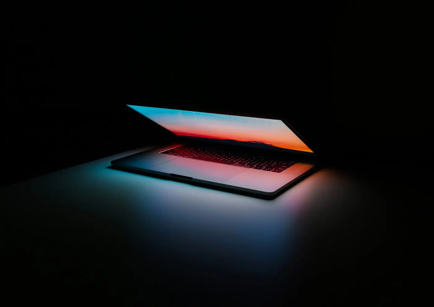 Half-open laptop glowing in the dark
